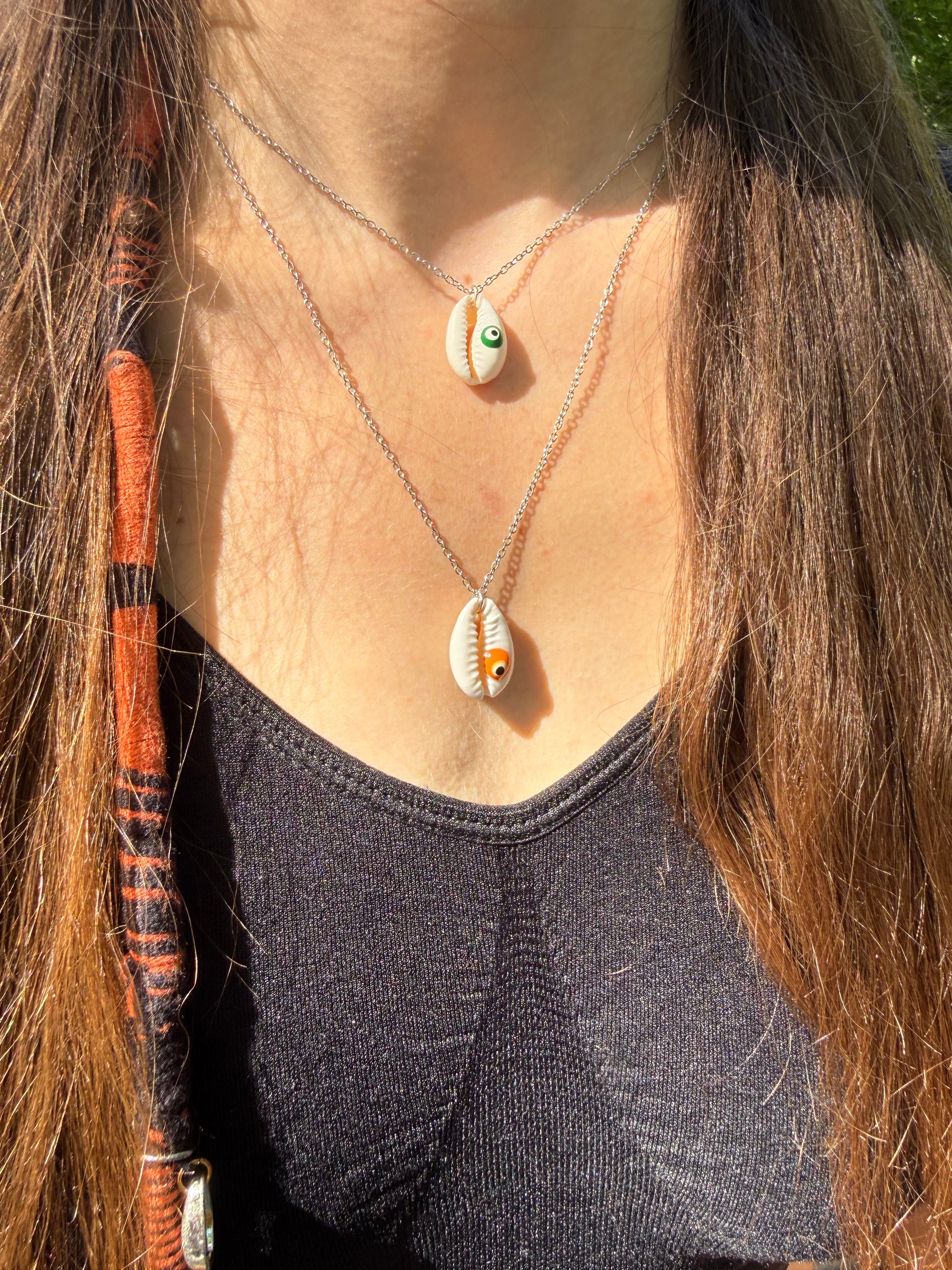 Collier cauri naturel avec œil protecteur vert et orange porté autour du cou en acier inoxydable 316L